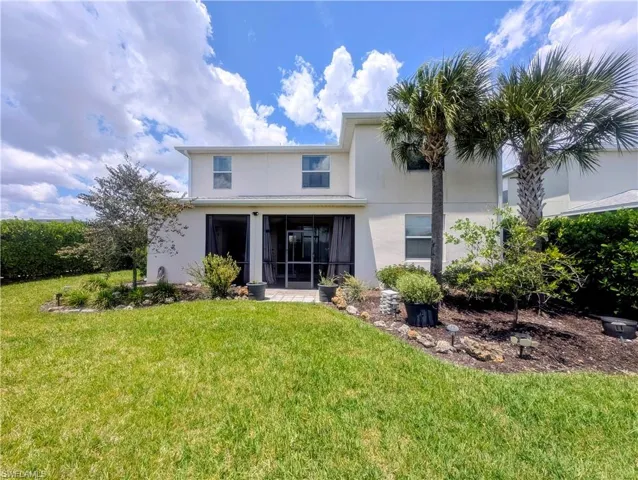 Expansive backyard featuring a screened patio with mature palm trees, and established landscaping