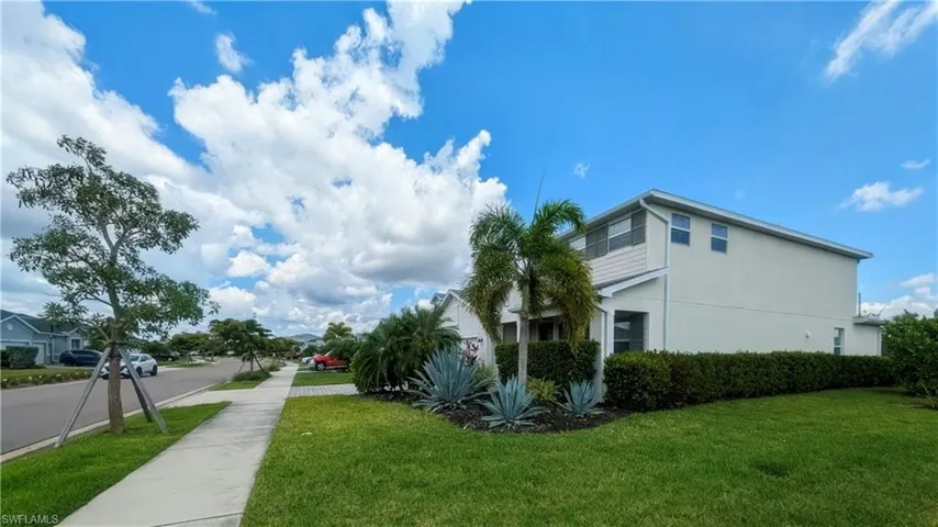 Contemporary two-story residence with a light-toned exterior, featuring a neatly maintained lawn and established landscaping