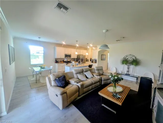 Open-concept living space featuring wood-finish flooring, recessed lighting, and crown molding