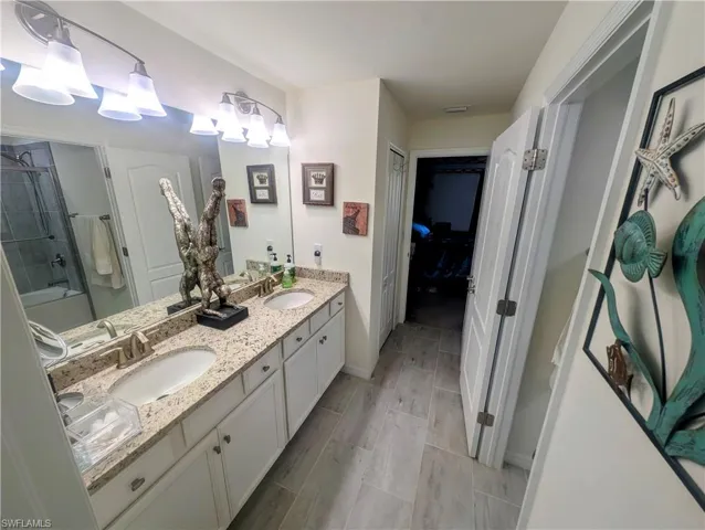 Double vanity featuring granite-style countertops, undermount sinks, and brushed nickel fixtures
