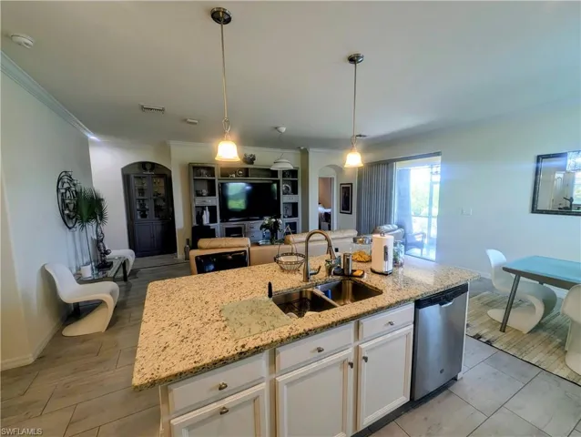 Kitchen island with granite countertop, double sink, and pendant lighting