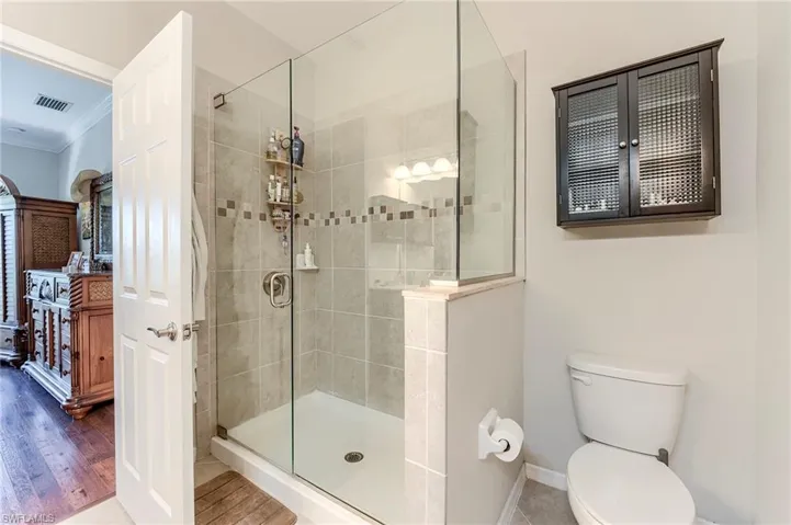 Full bathroom with crown molding, a stall shower, and wood finished floors
