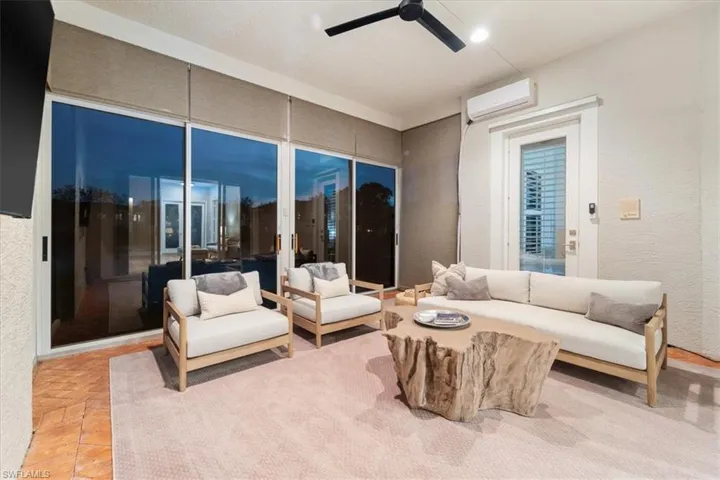 Living area with ceiling fan, a textured wall, and a wall unit AC