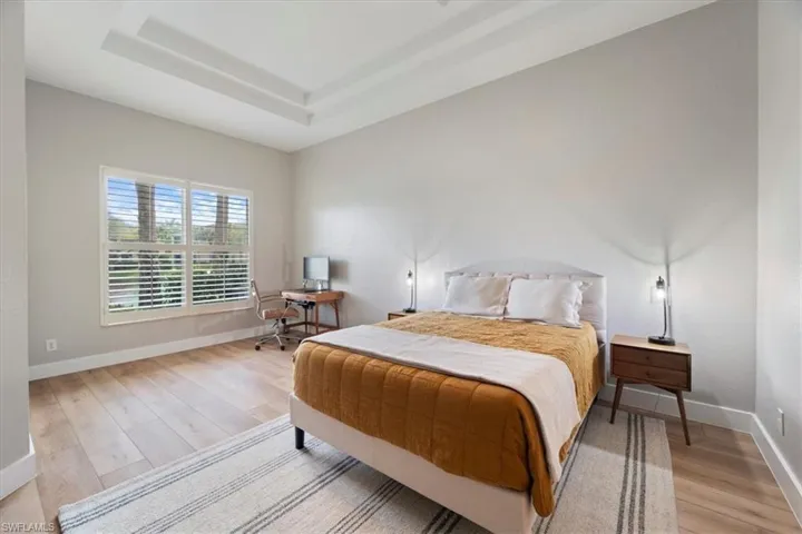 Bedroom with light wood-style floors, baseboards, and a raised ceiling