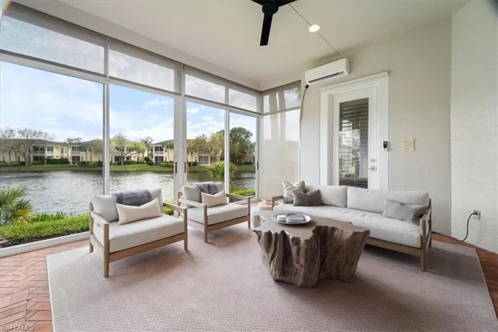 Sunroom / solarium featuring ceiling fan, a wall mounted air conditioner, and a water view