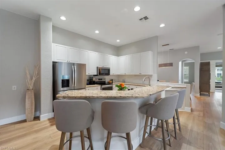 Kitchen with a breakfast bar, visible vents, stainless steel appliances, and backsplash