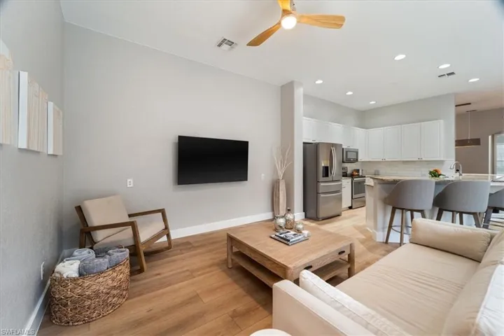 Living area with light wood-style floors, visible vents, ceiling fan, and baseboards