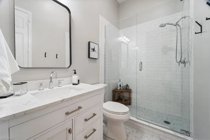 Bathroom featuring a stall shower, vanity, and toilet