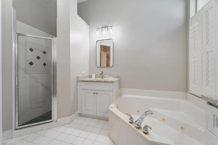 Bathroom with a shower stall, a tub with jets, tile patterned flooring, and vanity