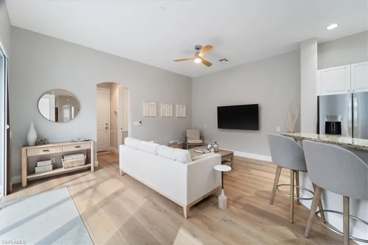 Living room featuring baseboards, arched walkways, a ceiling fan, light wood-style flooring, and recessed lighting