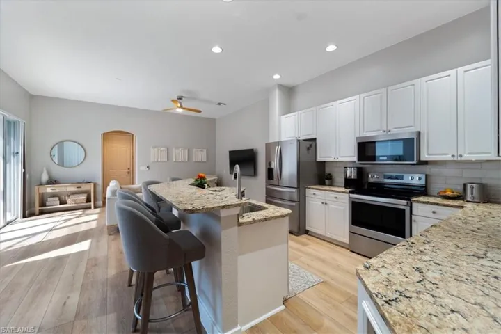 Kitchen with appliances with stainless steel finishes, arched walkways, light wood-style floors, and a sink