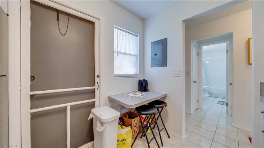White screen door, built-in wall table, white tiled flooring, white painted walls, and an interior hallway