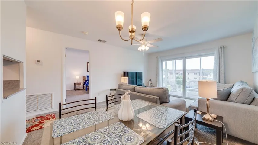 Open-concept living area with a glass-top dining table, a ceiling fan, and large sliding glass doors leading to an outdoor space
