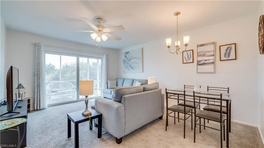 Open-concept living area with carpet flooring, a ceiling fan, and sliding glass doors