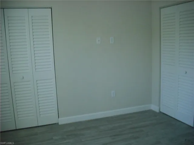 Unfurnished bedroom featuring baseboards, a closet, and wood finished floors