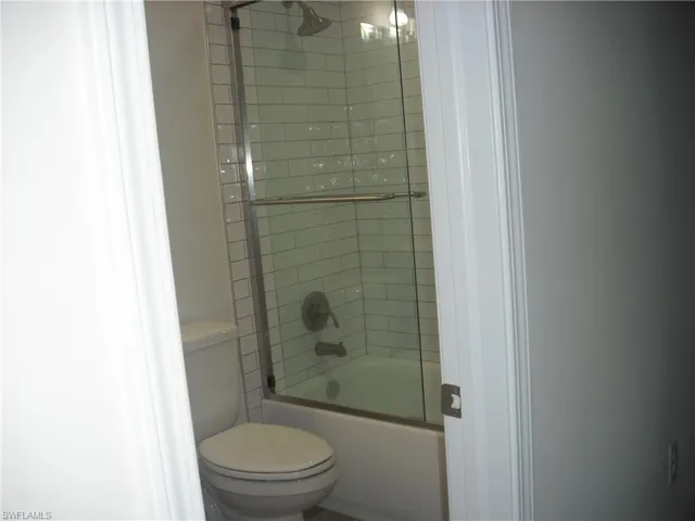 Full bath featuring toilet and bath / shower combo with glass door