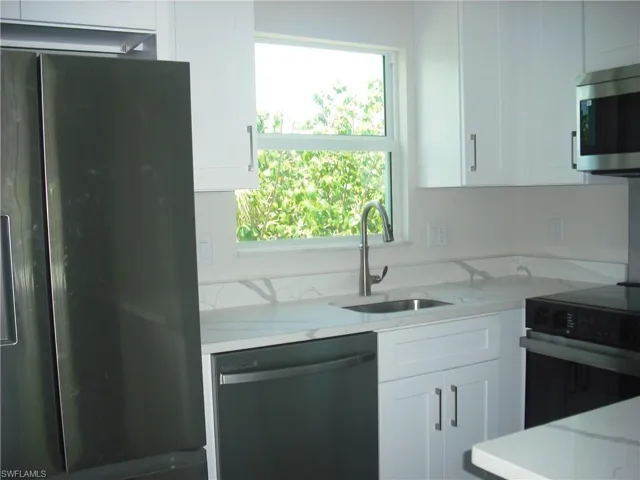 Kitchen featuring stainless steel appliances, white cabinetry, and plenty of natural light
