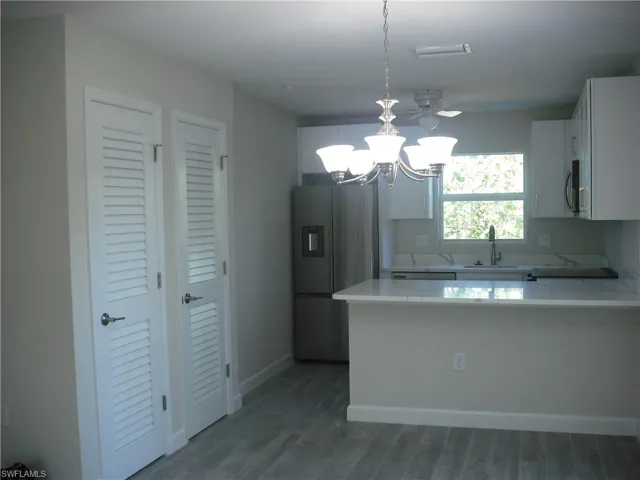 Kitchen with a notable chandelier, light countertops, a sink, a peninsula, and stainless steel appliances