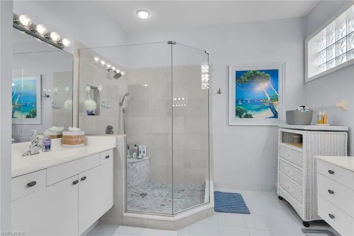 Bathroom featuring vanity, light tile patterned floors, and a shower stall
