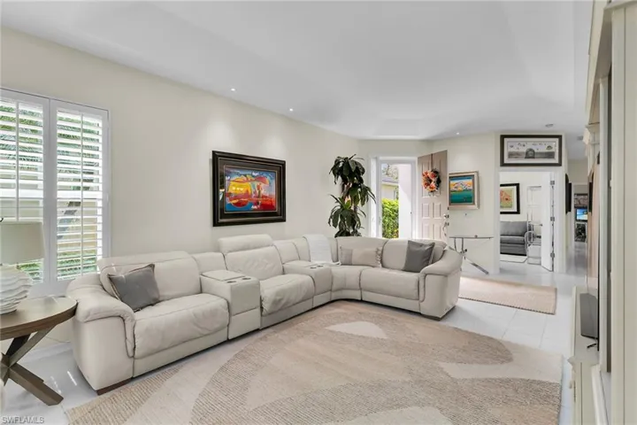 Living room featuring a tray ceiling, recessed lighting, and light tile patterned flooring