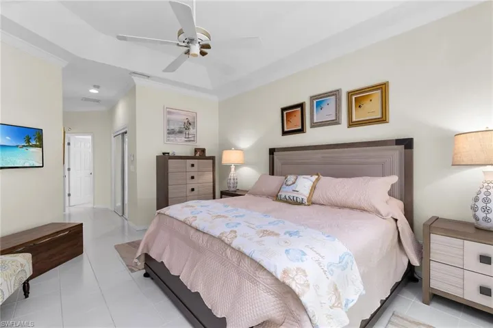 Bedroom featuring light tile patterned floors, a closet, ornamental molding, and a ceiling fan