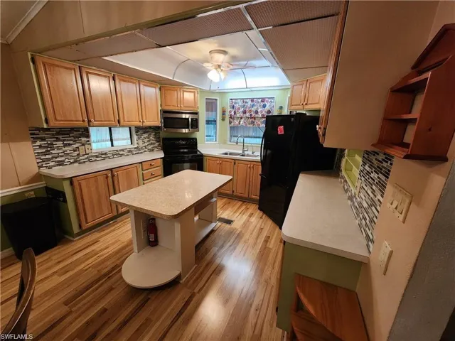 Kitchen featuring open shelves, light countertops, and black appliances
