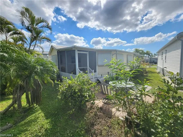 Back of property featuring a sunroom, a yard, and a patio area