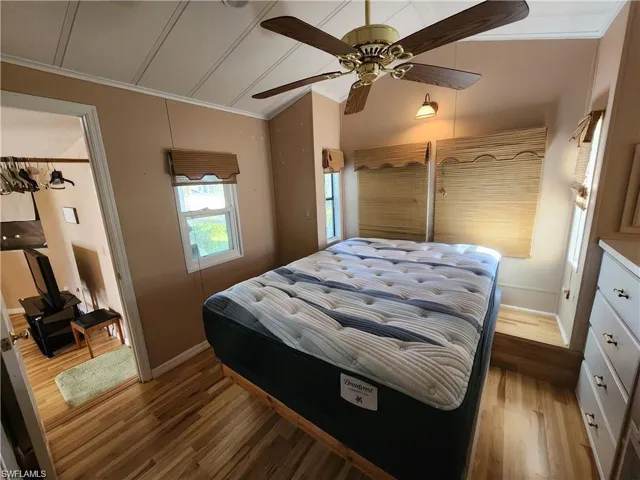 Bedroom featuring crown molding, light wood-style flooring, ceiling fan, and vaulted ceiling