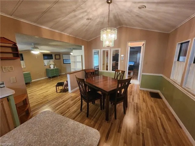 Dining area featuring light wood-type flooring, ornamental molding, a ceiling fan, and suspended lighting