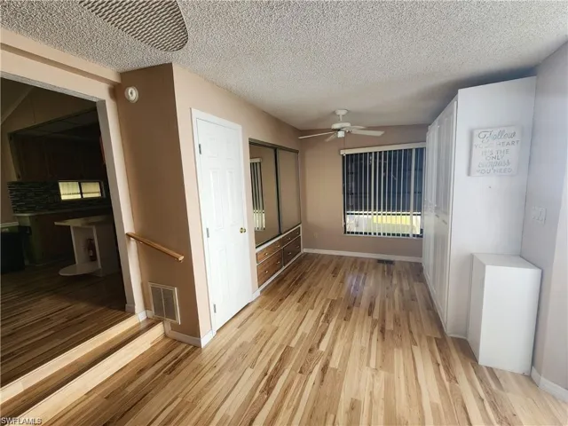 Empty room featuring light wood-type flooring, a textured ceiling, and ceiling fan