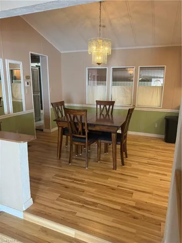 Dining space with light wood-type flooring, crown molding, vaulted ceiling, and a chandelier