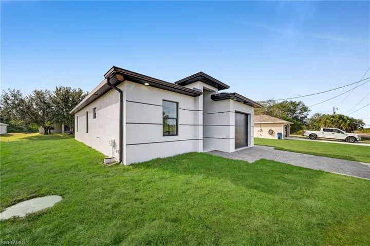 View of front of property with a front lawn, driveway, stucco siding, and a garage