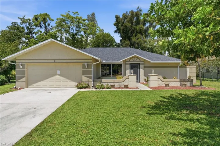 Contemporary stucco exterior featuring an attached two-car garage, dark shingle roof, concrete driveway, and front entryway with decorative columns