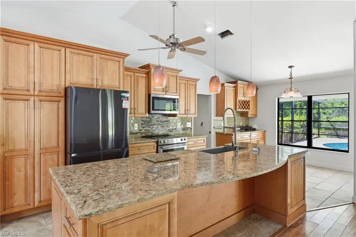 Kitchen featuring a curved granite-finish island with an undermount sink and gooseneck faucet