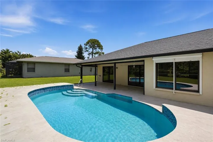 Curved-edge swimming pool with integrated steps, surrounded by a light-toned concrete deck