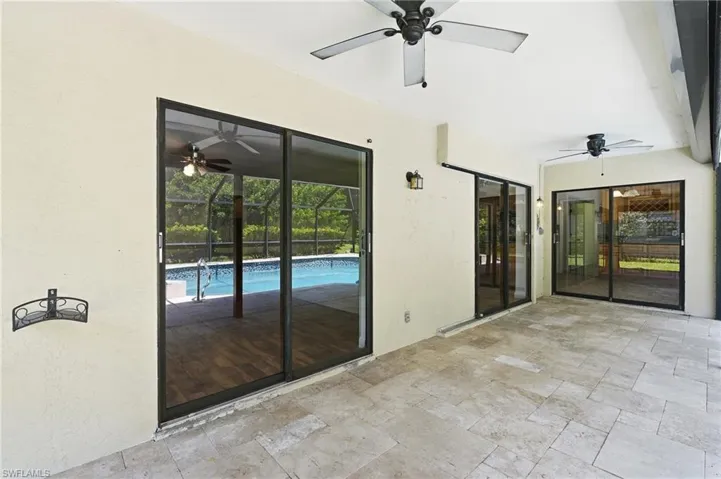 Covered patio featuring large format tile flooring, multiple ceiling fans, and several sets of sliding glass doors