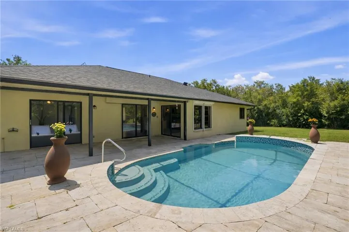 Exterior features an in-ground swimming pool with integrated steps, surrounded by stone paver decking
