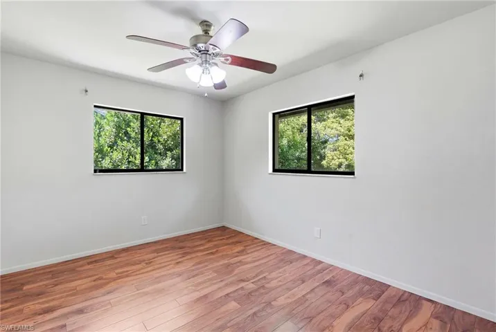 Bright interior space featuring wood-finish flooring, white walls, and a ceiling fan with integrated lighting