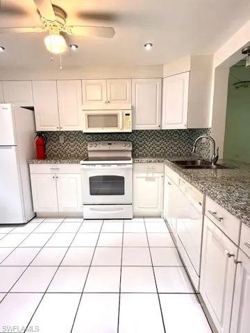 Kitchen featuring white cabinetry, white appliances, light tile patterned flooring, and recessed lighting