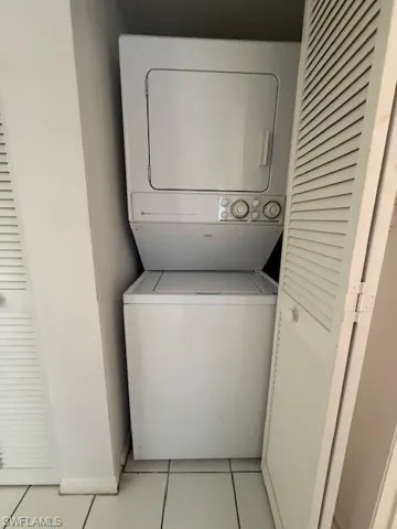 Washroom featuring light tile patterned floors and stacked washer and clothes dryer