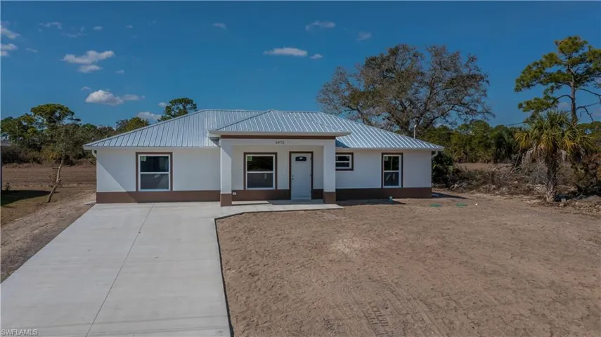 View of front of home featuring a porch, driveway, and a metal roof