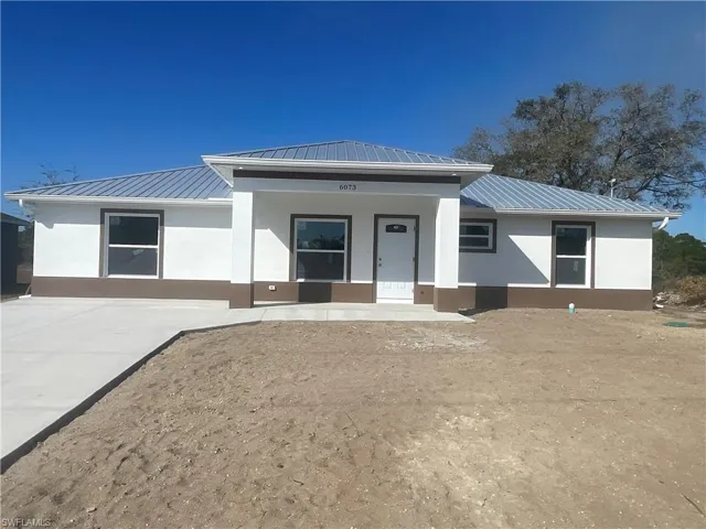 View of front of home with a metal roof, stucco siding, and covered porch