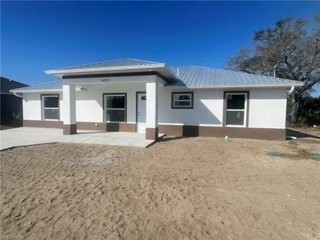 View of front of property with a metal roof, stucco siding, and a porch
