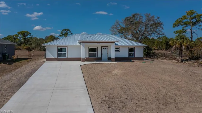 View of front of house featuring concrete driveway, a metal roof, stucco siding, and a porch