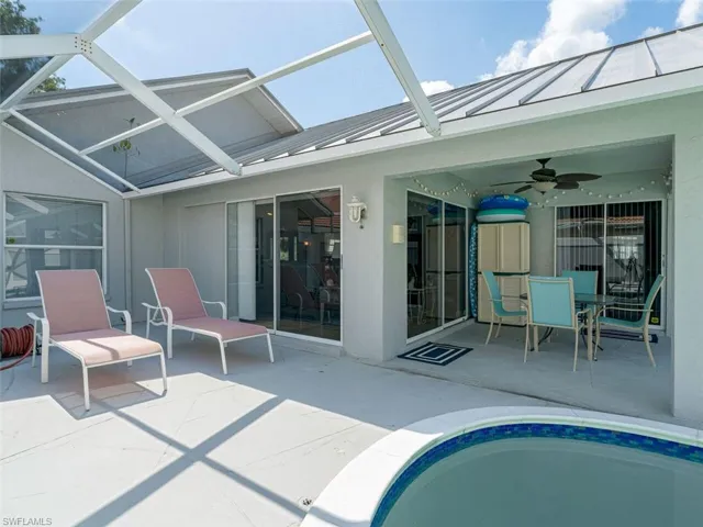View of pool with a patio, glass enclosure, and ceiling fan