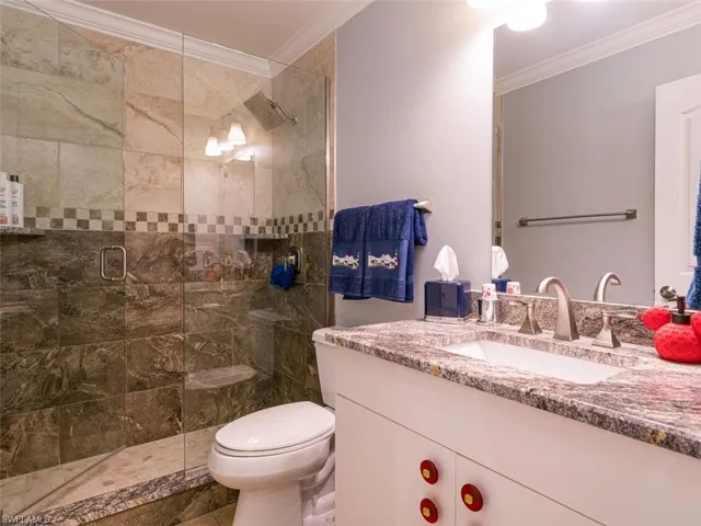 Bathroom with oversized vanity, a shower with shower door, tile floors, ornamental molding, and toilet