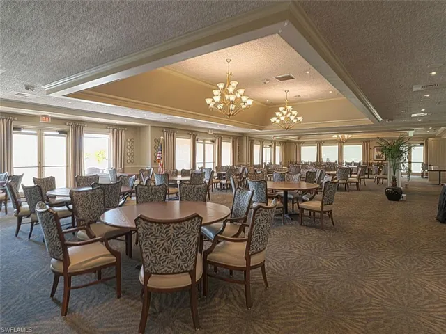 Carpeted dining area featuring an inviting chandelier, ornamental molding, a tray ceiling, and a textured ceiling