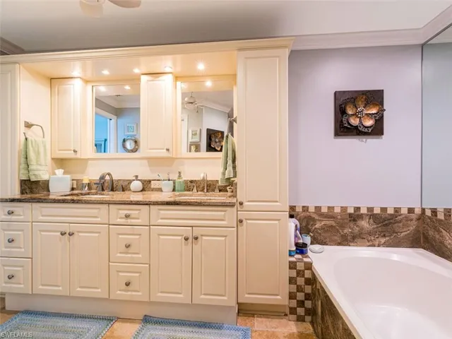Bathroom featuring dual bowl vanity, ceiling fan, tiled bath, and ornamental molding