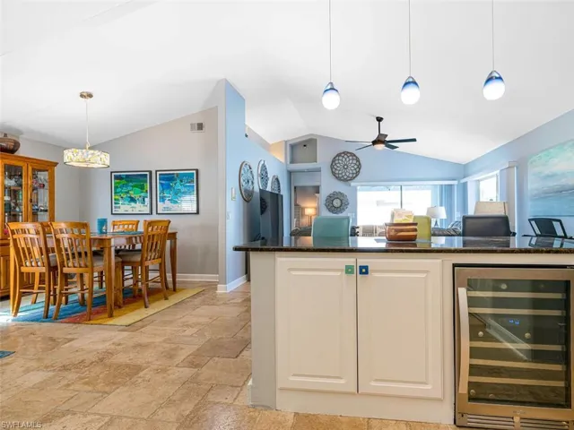 Kitchen featuring beverage cooler, decorative light fixtures, vaulted ceiling, and light tile floors