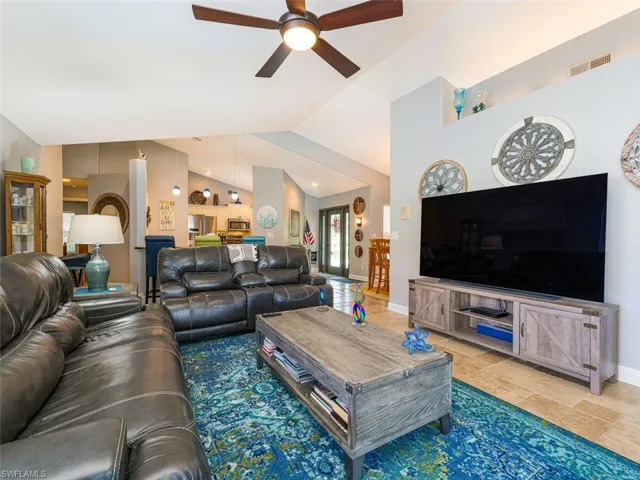 Tiled living room featuring ceiling fan and vaulted ceiling